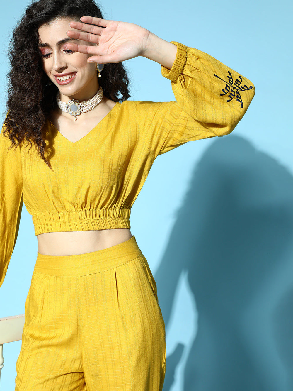 Women Mustard Self Weave Rayon Co-ords Set Has Crop Top With Round Neck, Elastic At Waistline, Gathers All Over At Waist, Full Sleeves Has Elastic At The Hem, Thread Embroidery At Sleeves, Mustard Palazzo Has Flared Hem With Side Slit, Both Side Pocket And Partially Elastic At Waistline